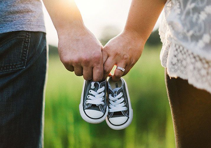 Man and Woman Holding Baby Shoes in Hands Man and Woman Holding Baby Shoes in Hands